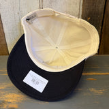 Black and natural Workhorse Hat with sunset design, made of fabric and mesh, displayed on a wooden surface.