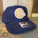 Navy corduroy baseball cap with classic logo, displayed on a rustic wooden surface.
