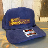 Navy blue corduroy baseball cap with sun patch, displayed on a wooden surface. Suitable for casual wear.