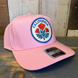 Pink 5-panel mid-profile baseball cap with a red poppy patch, suitable for casual wear.