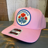 Pink 5-panel mid-profile baseball cap with California poppy design, cotton material, displayed on a wooden surface.