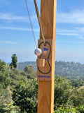 Ring toss golf putting game with a wooden post, set outdoors with green trees and hills in the background.