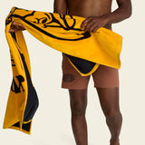 Person holding a yellow towel with black monkey patterns on a beige background.