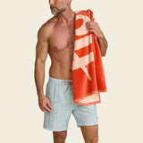 Man holding a red and white striped towel against a beige background.
