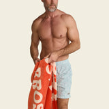 Man holding an orange towel with text on a beige background.