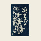 Navy blue towel with white graphic design and 'Howler' branding on a beige background.