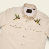 Zoomed beige shirt with embroidered hummingbirds on a beige background.