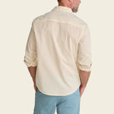 A man's back view, wearing a beige shirt and light blue pants on a plain background.