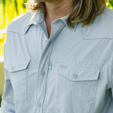 Person with long blond hair wearing a sky blue long sleeve tech shirt, UPF 35; upper body shown.
