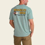 Person wearing a light blue t-shirt with 'Howler Bros' logo on the back, standing against a beige background.