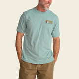 Person wearing a light blue t-shirt with 'Howler Bros' logo, standing against a beige background.