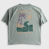 Aqua cotton pocket tee featuring palm trees, waves, sun, and logo text graphic on the back; casual wear.