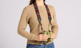 Person in a tan sweater uses a woven tapestry strap with green binoculars, showing its fit and material.