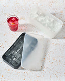 Charcoal silicone ice trays next to a red iced drink with lemon slices.