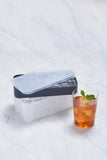 Charcoal silicone ice tray and storage box next to a mint-garnished iced drink on a marble surface.