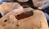 A black waterproof monocular with a textured grip sits on ice, sunlight emphasizing its rugged cylindrical design.