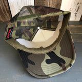 Camouflage trucker hat shown inside out on a wooden surface, highlighting mesh and fabric details.