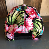 Pink hibiscus Hawaiian print cap in back view, cotton material, displayed on a wooden surface.