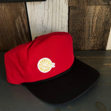Black and red five-panel cap with high crown, mini sunburst logo patch, suitable for casual outdoor wear.
