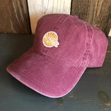 Maroon 6-panel cotton dad hat with mini logo detail placed on a wooden surface.