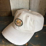 Stone-colored dad hat with front patch, cotton material, displayed on rustic wood surface.