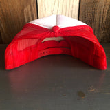 Black and white trucker hat with mesh panels lies upside down on a dark wooden surface.