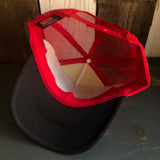Black, white, and red trucker hat with adjustable snapback, displayed upside down on a wooden surface.