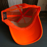 Neon orange and white trucker hat viewed from above, highlighting mesh material, interior lining, and tag.