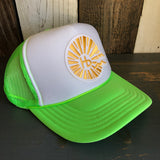Neon green and white trucker hat with mesh panels rests on a wooden surface.