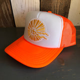 Neon orange and white trucker hat with classic logo, mesh panels, and curved brim set on a dark surface.