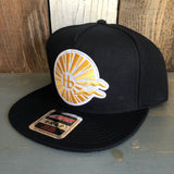 Black 5-panel OTTO SNAP hat with classic logo, made of fabric, displayed on a wooden surface.