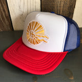 Red, white, and royal blue trucker hat with mesh back and classic logo, displayed on a wooden surface.