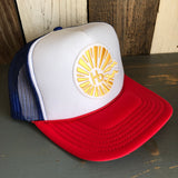 Trucker hat with red bill, white front panel, blue mesh back, yellow sun logo, and adjustable snapback closure.