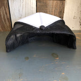 Black and white trucker hat with mesh back displayed upside down on a rustic wooden surface.