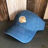 Blue cotton baseball cap with embroidered yellow sun patch on rustic wood background
