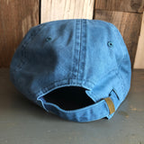 Blue cotton dad hat with adjustable brass strap, back view on rustic wood surface